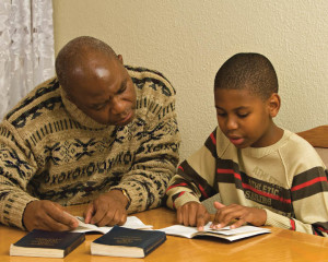A father studying scriptures with His son.